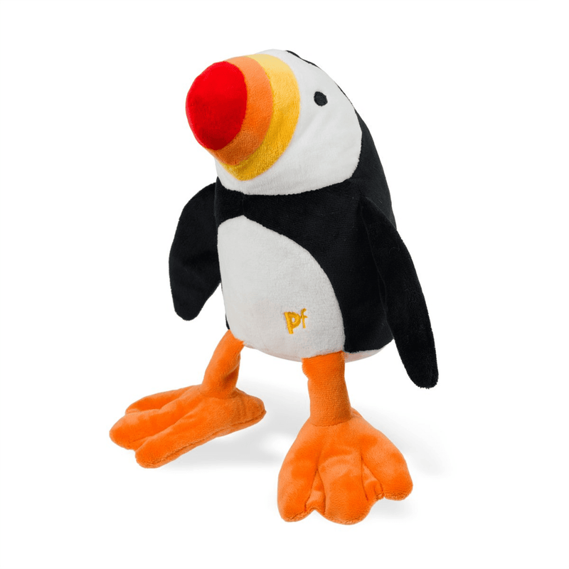 Plush Puffin dog toy with a red, orange and yellow beak and orange feet, standing on a white back ground. 