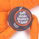 Close up of tag with text that says 'tuff inner bouncy frame' and 'Feels like a stuffed toy but with no messy stuffing!' attached to the leg of orange plush dog toy on a white background.