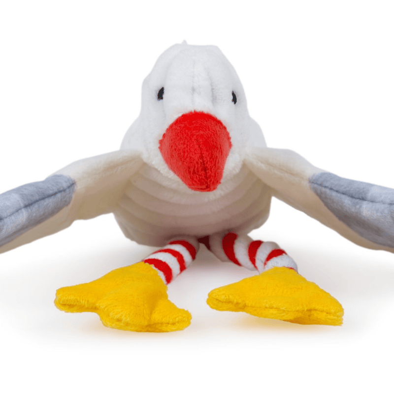 Close up of front of seagull dog toy with a white body, grey and blue wings and tail. Orange beak and yellow feet with red and white rope legs. Sat on a white background. 