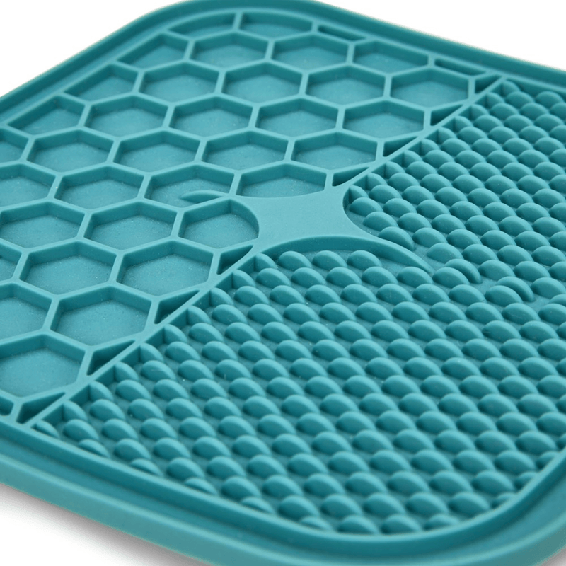 Close up of blue silicone lick mat with two different textures, one with hexagon shapes, the other with small close together ridges pictured on a white background. 