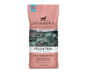 A bag of Skinner's Field & Trial Salmon & Rice dog food for adult working dogs, featuring a dusty pink packaging design with a central illustration of a hunting scene.