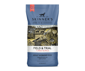 A bag of Skinner's Field & Trial Turkey & Rice dog food for adult working dogs, featuring a blue packaging design with an illustrated rural scene in the center.