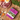 A box of Skinner's Field & Trial dog food placed on a wooden cutting board, surrounded by raw meat, vegetables, and herbs. The packaging is predominantly purple and white with an illustration of a farm scene.