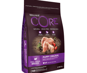 White background with a picture of a bag of Wellness CORE Original Puppy Food. On the bag is pictures of chicken leg, turkey fillet, blueberries and tomatoes. The text on the bag 'Wellness CORE, Natural, Grain Free, Protein-Rich' and 'Small/Medium breed, Puppy Original, Turkey with Chicken Recipe'. 